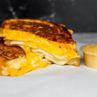 Roasted Turkey & Three Monte Cristo · Roasted turkey breast, Cheddar, Swiss, and Parmesan cheeses melted between egg dipped, gridd...