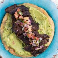 Crunchy Arepa Con Churrasquito · Deep fried corn cake spread with guacamole topped with skirt steak and pico de gallo.