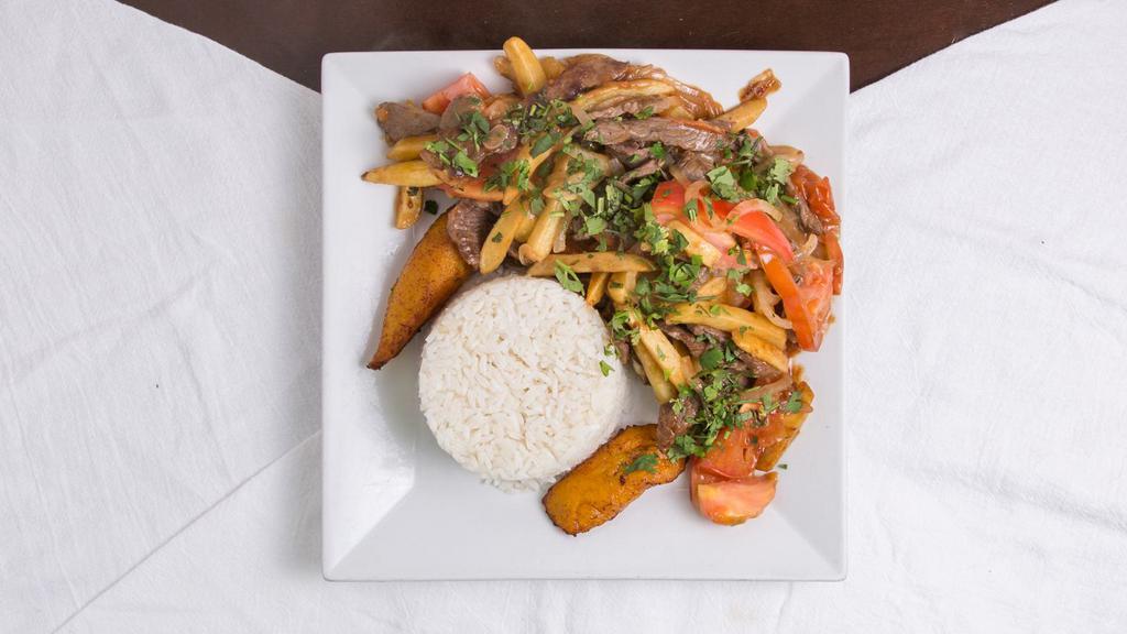 Lomo Saltado · Stir-fried pork loin, onions tomatoes, spices, French fries. Served with fried plantains and white rice