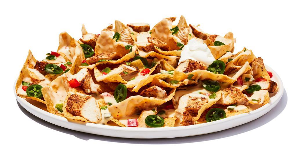 Tex-Mex Nachos Chicken · Tortilla chips layered with cheese, grilled chicken topped with shredded lettuce, pico de gallo, fresh jalapenos, sour cream, and a chipotle sauce. 1585 cal.