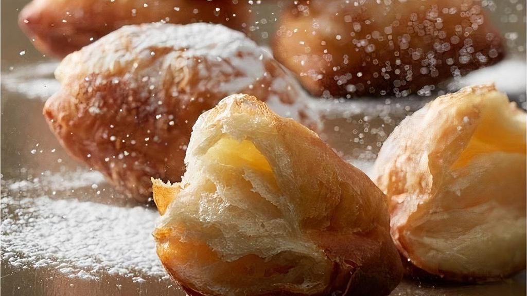 Croissant Beignet · Our Croissant Beignet is a flaky spin on the traditional beignet. As a feature in homestyle Creole cooking, beignets are typically made from deep-fried choux pastry. By utilizing croissant dough instead, our Croissant Beignet maintains a flaky texture and a soft, richly flavored interior. Dusted with confectioner’s sugar
