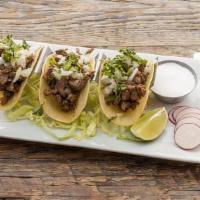 Steak Tacos (Tacos Al Carbon) · Grilled skirt steak tacos, topped with white onions, cilantro, radish, and torero sauce.