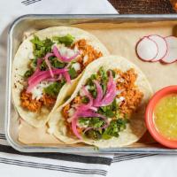 Tinga Chicken · Braised chicken with chipotle peppers, topped with onions, cilantro, and pickled onions.