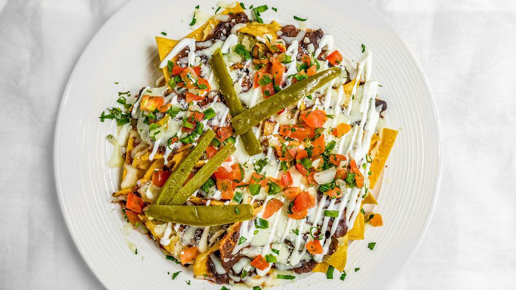 Nachos · Deep-fried corn tortillas with refried beans, pico de gallo, mozzarella cheese, jalapeños, Cotija cheese and sour cream. Add protein for an additional charge.