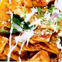 Chilaquiles Regulares · Crispy corn tortilla cooked in green or red salsa topped with onions, avocado, sour cream an...