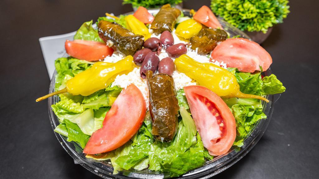 Greek Salad · Our Greek salad is made with romaine and iceberg lettuce, scallions, green and red bell peppers, radishes, cucumbers, feta cheese, dolma, pepperoncini, black olives, tomatoes and our famous dressing, served with pita bread.