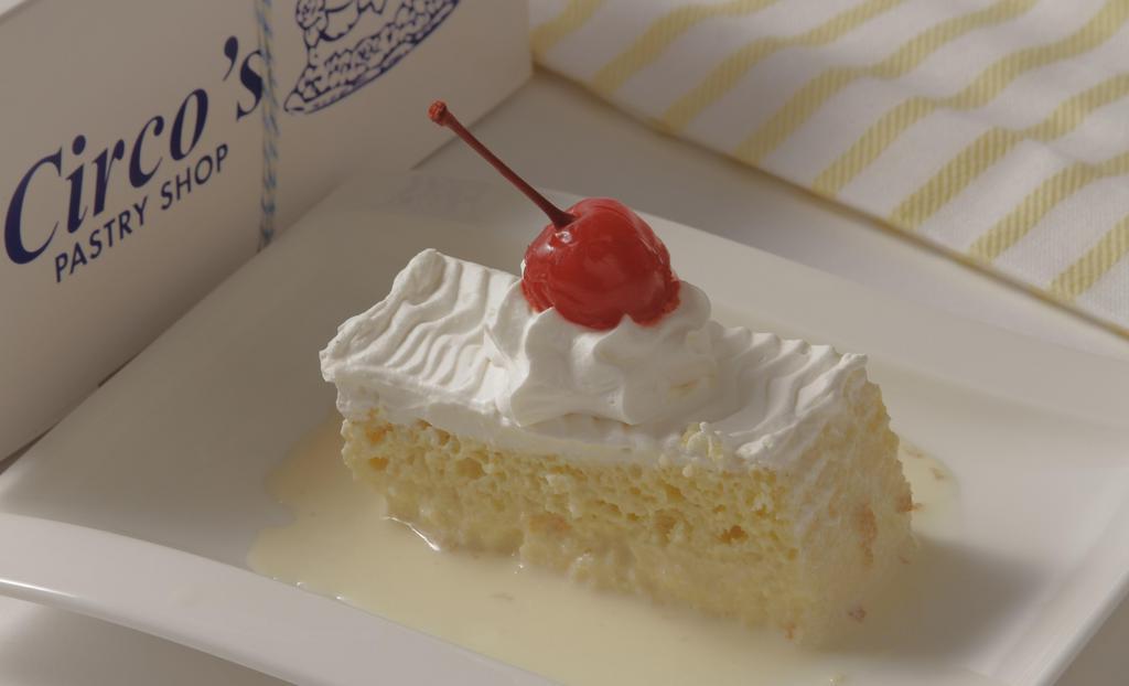Tres Leches Pastry · A butter cake soaked in three kinds of milk: evaporated milk, condensed milk, and heavy cream. Topped with whipped cream and a maraschino cherry.