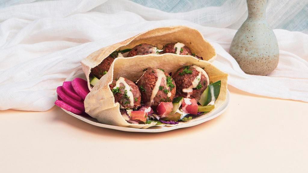 Classic Falafel Pita Sandwich · Falafel with shredded cabbage, diced tomato and cucumber, and a tahini drizzle wrapped up in a fresh pita.