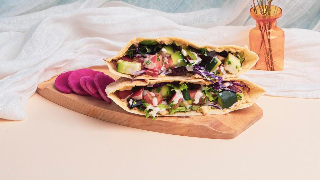 Hummus Pita Sandwich · Hummus with shredded cabbage, diced tomato and cucumber, and a tahini drizzle wrapped in a fresh pita.