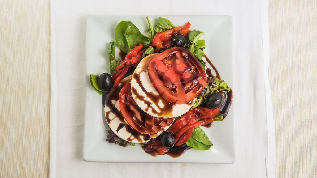 Fresh Mozzarella And Tomato · Homemade fresh mozzarella, sliced tomato and roasted red peppers served on a bed of spring lettuce and drizzled with balsamic glaze. Served with a side of balsamic and oil. *
