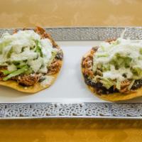 Tinga Tostada · Shredded chicken in a chipotle sauce. A deep-fried tortilla topped with lettuce, beans, coti...