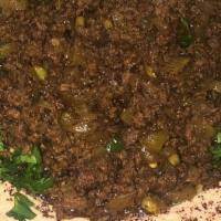 Hummus With Lahmeh · A plate of hummus surrounding lahmeh (ground beef and lamb cooked with onions garlic and jal...