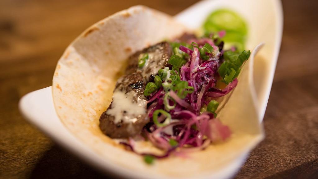 Galbi Taco · Premium short rib beef marinated in traditional galbi sauce with fresh ginger cabbage slaw, lettuce, and carrots topped with house-made kiwi sauce. Single serving.