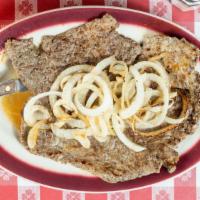 Bistec Rincon Criollo · Palomilla steak on the grill topped with cooked onions.