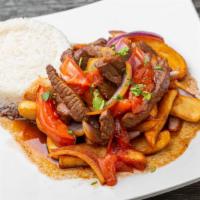 Peruvian Lomo Salteado · Chunks of sirloin, red onion, tomato slices, served over french fries and accompanied with w...