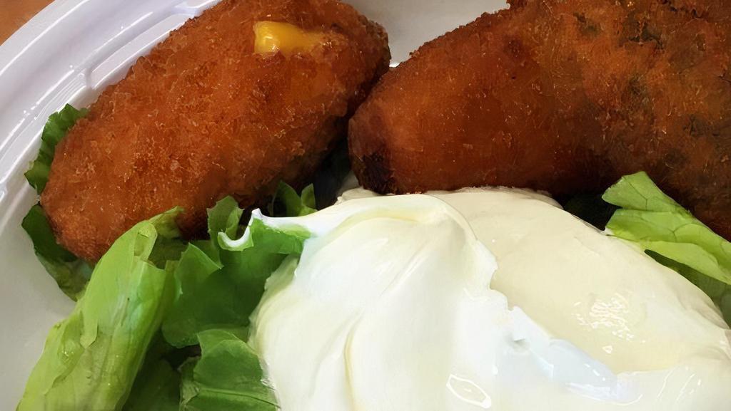 Jalapeno Poppers · Breaded jalapenos stuffed with cheddar cheese. Served on a bed of lettuce and a side of sour
cream.