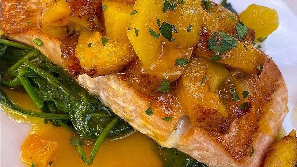 Salmon Varadero · Pan seared wild caught Atlantic salmon served with sautéed spinach and maduro chips topped with mango sauce.