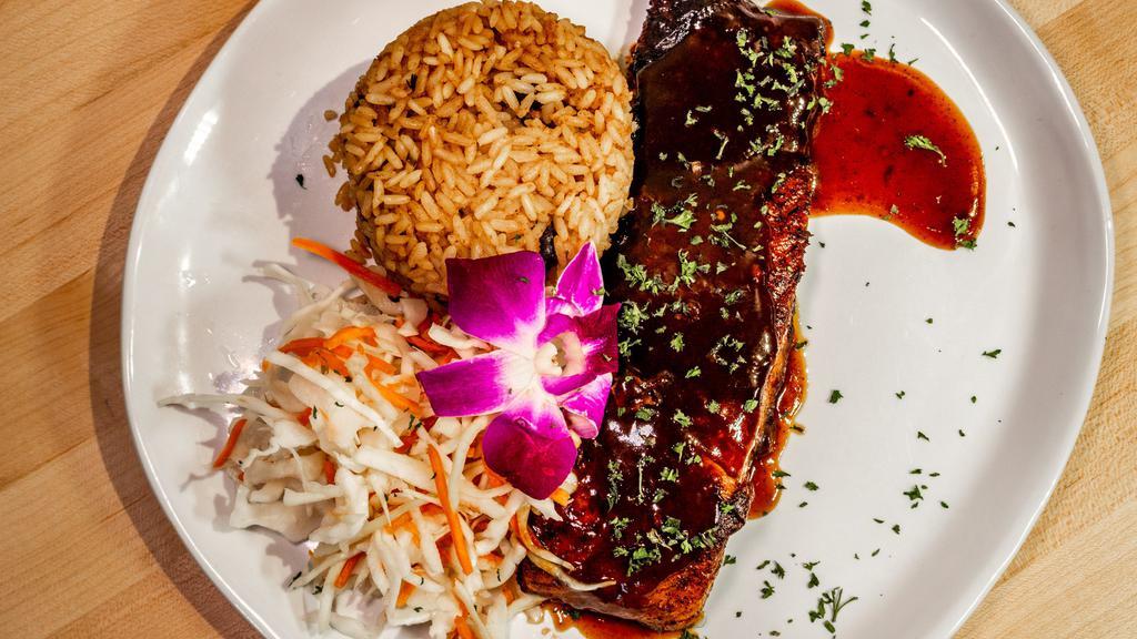 Jerk Salmon · Wild caught 8-10 oz salmon fillet, pan seared then cooked with house-made jerk sauce. Served with white rice are rice n peas, cabbage slaw and fried plantains.