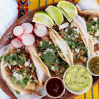 Al Pastor Street-Style Tacos · 4 soft shell tacos topped with cilantro and onions. Served with avocado salsa and red spicy ...