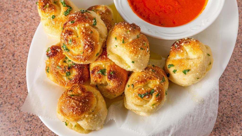Garlic Knots · A classic snack, our garlic knots are strips of pizza dough tied in a knot, baked and then topped with melted butter, garlic and parsley.