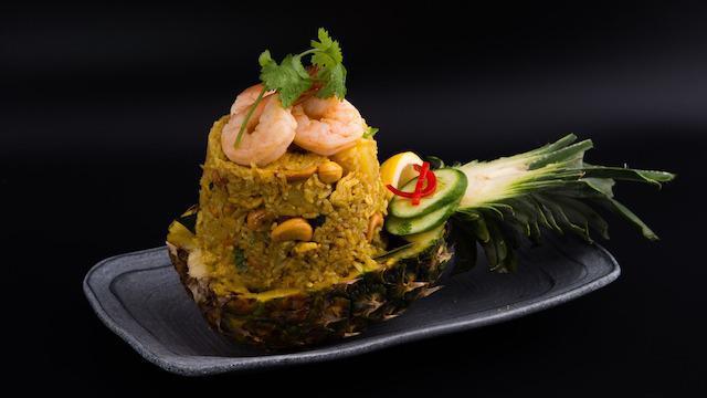 Pineapple Fried Rice · Stir-fried jasmine rice with Shrimp, pineapples, onions, scallions, tomatoes, carrots, curry powder & egg garnished with roasted cashew nuts.