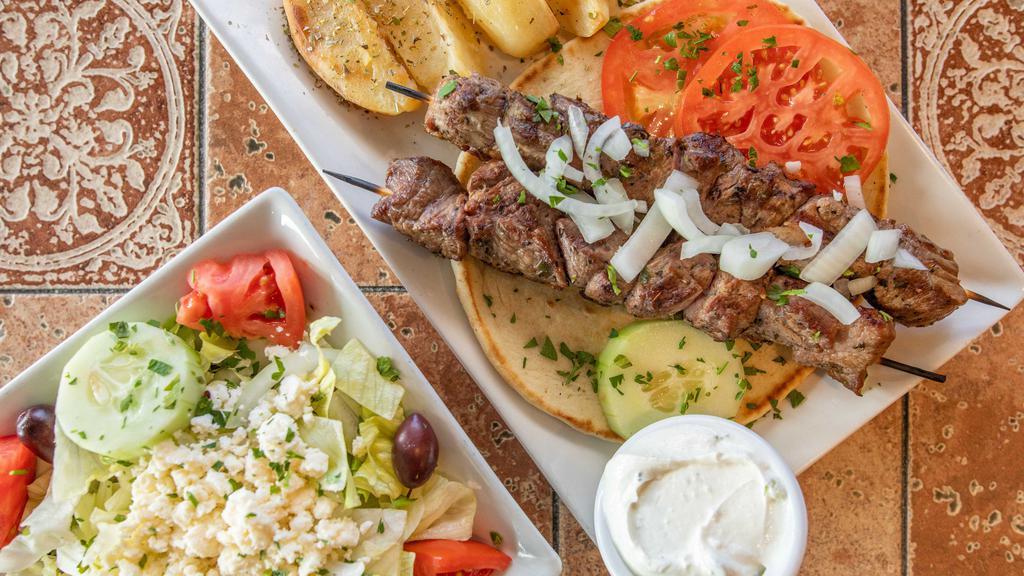 Lamb Shish Kebab Platter · 2 skewers Chargrilled. Served with Greek salad, pita bread, tzatziki sauce, garnished with tomato, onions, and cucumber.