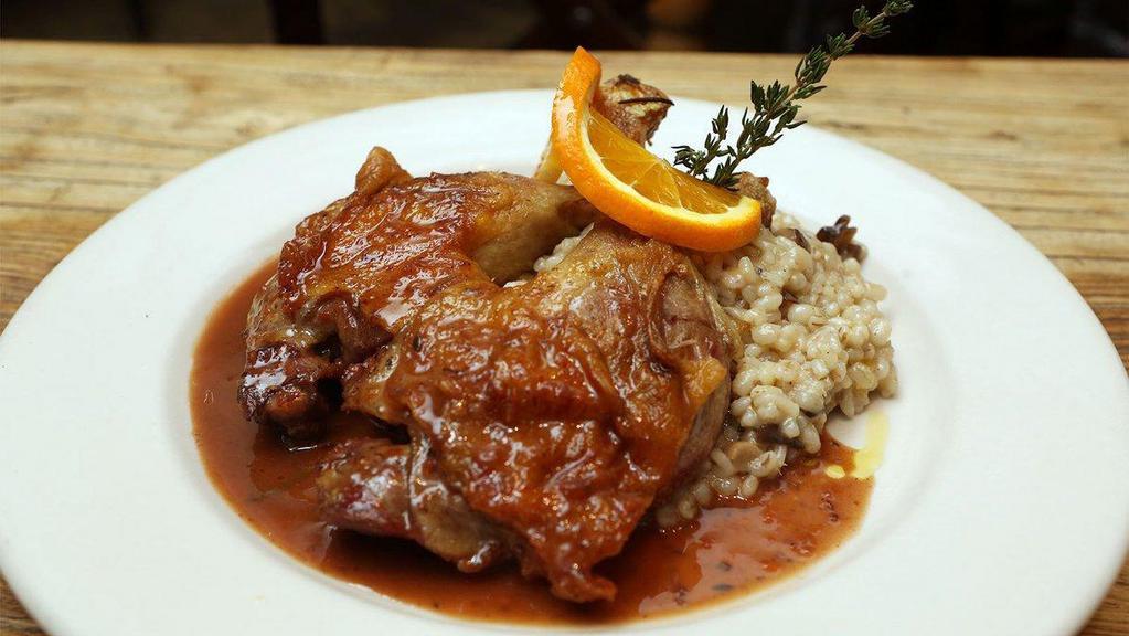 Duck Legs Confit · Slow-braised duck legs, grand marnier, and orange reduction, served with blueberry barley risotto.