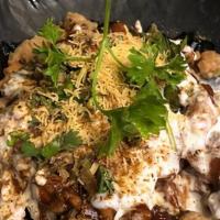 Veggie Samosa Chaat · Veggie samosa with chickpea curry, spices and sauces on it..