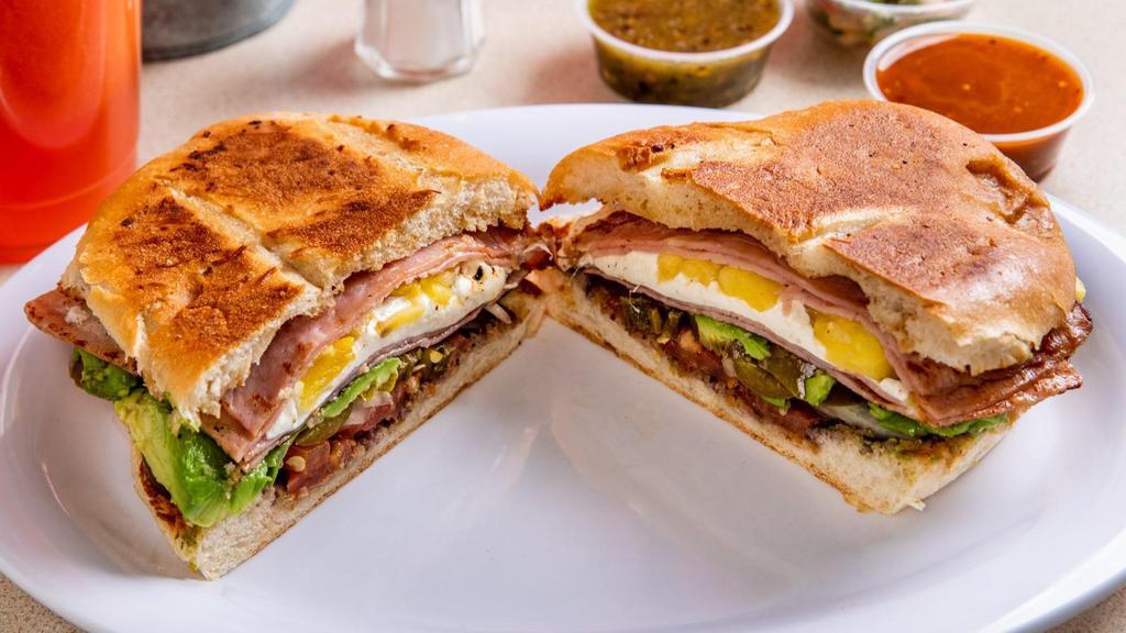 Cubana Torta · Traditional Mexican sandwich served on a telera toasted bread with refried beans, mayo, sliced tomato, onions, jalapeno and fresh avocado. Steak, hotdog sausage, ham, eggs and cheese.