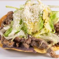 Steak Tostadas · Crunchy tortilla with refried beans, lettuce, avocado, Cotija cheese and sour cream.