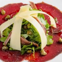Bresaola · Thinly sliced cured Dried Beef, Arugula Salad with Parmesan Cheese, Anchovies and Capers.