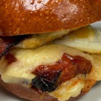 Classic Brekkie Sanga · Two eggs over easy, roasted tomato, sharp cheddar and applewood smoked bacon on a brioche bun.