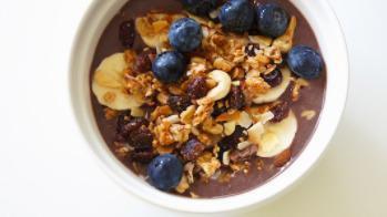 Rio Crunch Granola Bowl · Acai bowl topped with layer of granola (bottom - middle - top), bananas, and honey.
