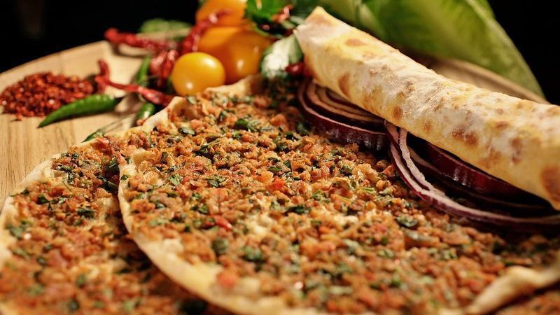 Lahmacun · Two pieces. A Turkish style pizza. Flat bread dough topped with lamb and chopped garden vegetables.