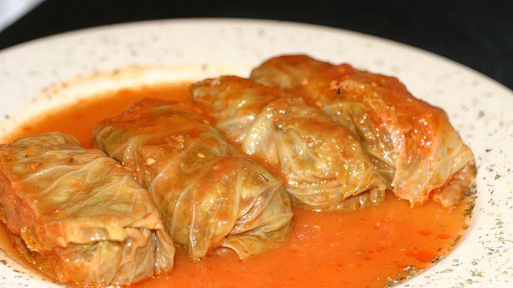 Stuffed Cabbage · Boiled cabbage leaves filled with a mixture of ground lamb, beef, rice, and herbs. Served with salad and yogurt.