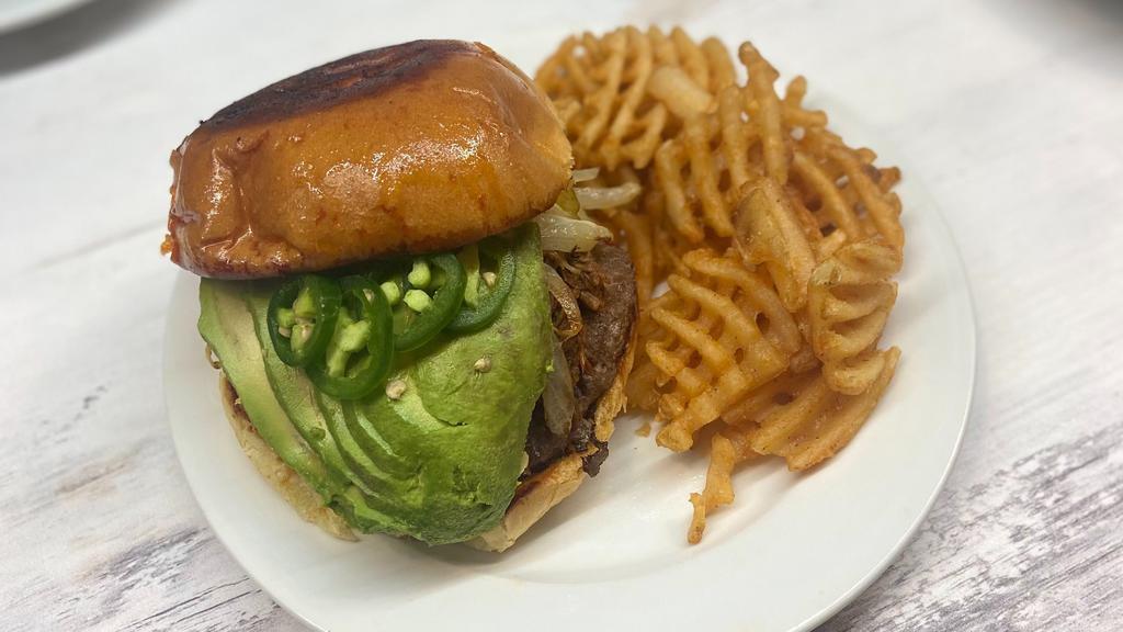 Birria Burger · Beef Burger, chopped birria, melted mozzarella, jalapenos, onion & peppers, sliced avocado onions, cilantro, on a toasted bun served with consome.