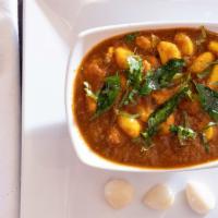 Karuveppilai Poondu Kuzhambu · Tamarind based tangy curry cooked with whole garlic, onions, curry leaves and tomatoes.