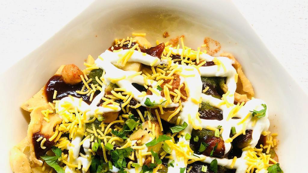 Papdi Chaat · Papdi (crispy dough wafers) topped with chickpeas, potatoes, yogurt, mint and tamarind chutney, coriander and sev( crunchy seasoned noodles).