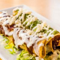 Flautas De Pollo · Two crispy tortillas filled with shredded chicken, topped with salsa verde, pasilla de oaxac...