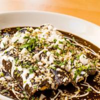 Enchiladas De Mole Negro Oaxaqueño · Soft corn tortillas filled with braised chicken topped with a stone-ground oaxacan black mol...