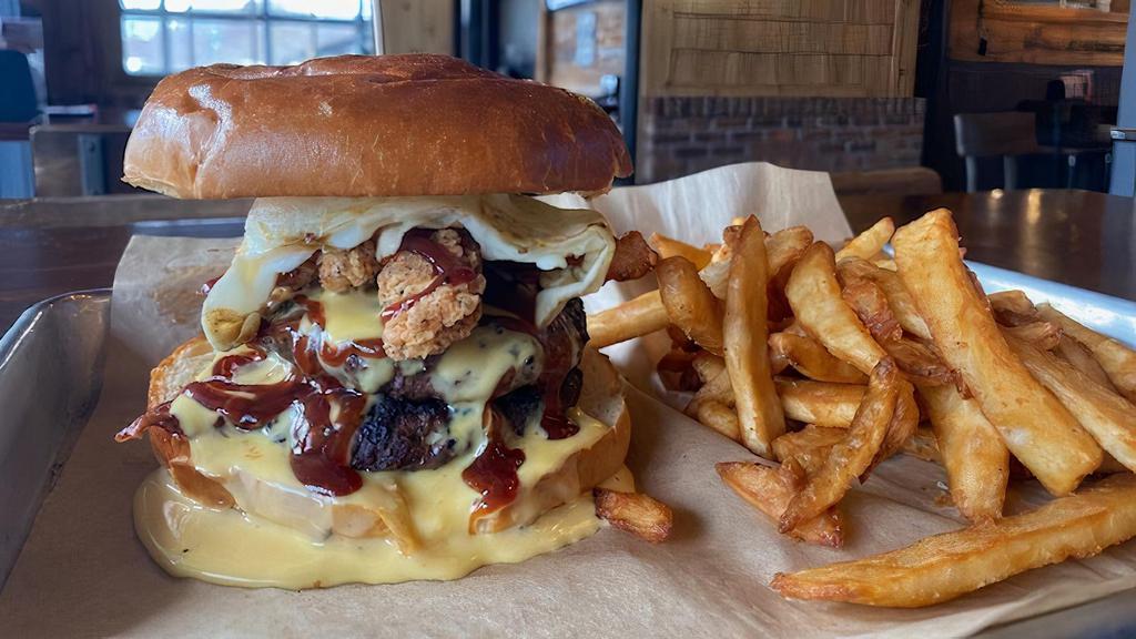The Hooligan Burger · Two beef patties layered with bacon, chicken tenders, cheese sauce a fried Hooligan burger egg, and topped with BBQ sauce. Served “pink or no pink” with French fries.
