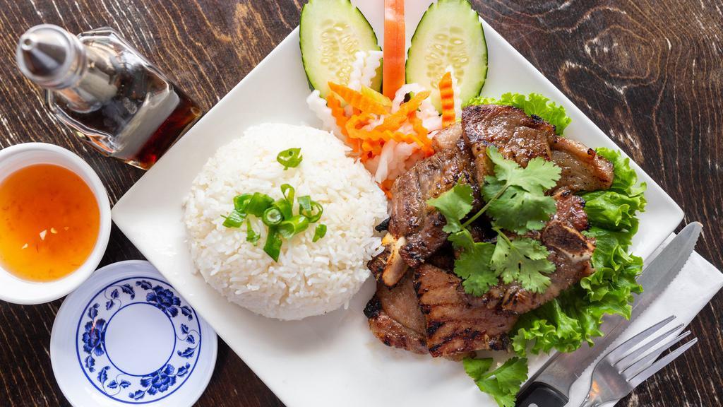 Com Suon Nurong · Pork chop rice. Grilled pork chop served on rice with cucumber and tomatoes.