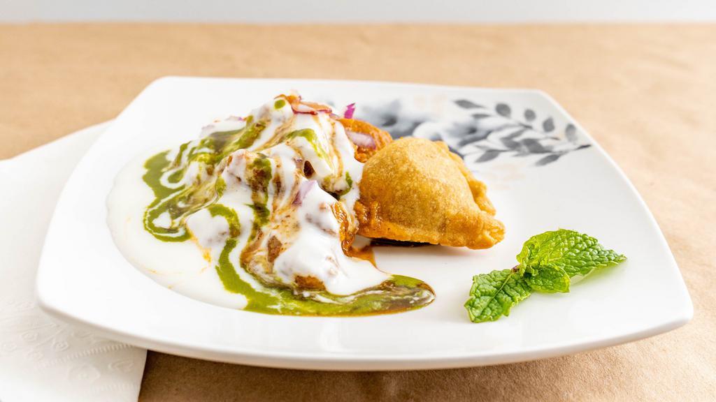 Samosa Chaat · Crispy samosa topped with chickpeas masala, yoghurt, tamarind date, cool mind and coriander chutney.