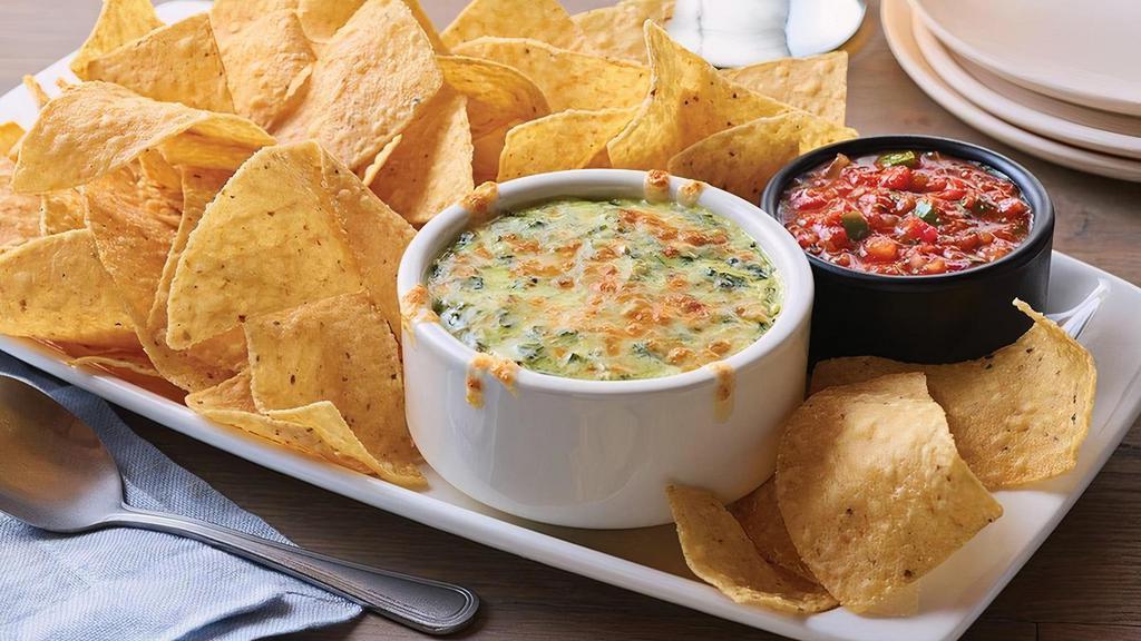 Spinach & Artichoke Dip · Creamy spinach and artichoke dip topped with Parmesan cheese.  Served with freshly made white corn tortilla chips and our chipotle lime salsa.