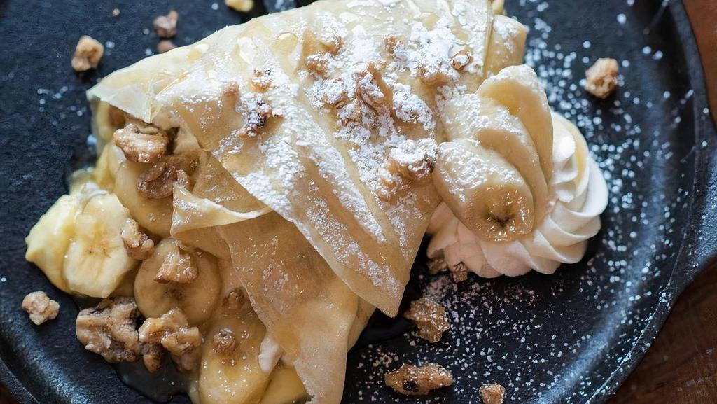 Bananas And Cream Crepe · Fresh banana sauteed in butter and brown sugar, with creme brulee custard, candied walnuts & whipped cream