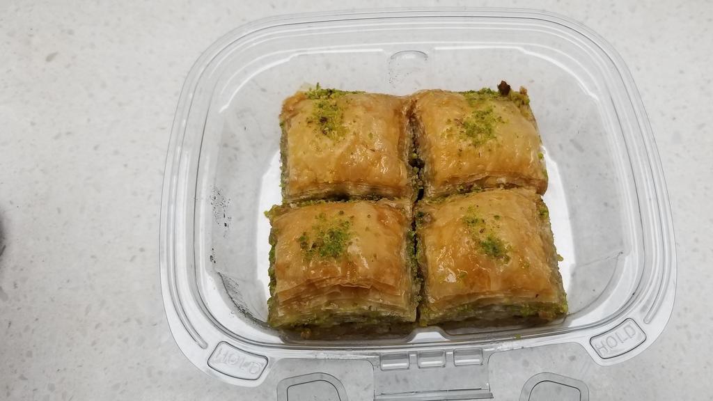 Baklava · a Near Eastern pastry made of many layers of paper-thin dough with a filling of ground nuts, pistachio baked and then drenched in a syrup of honey. Four Bite size pieces in a box.