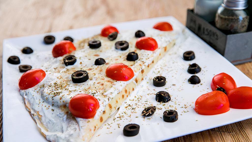 Greek Wrapped Omelette · Feta, spinach, and tomato tucked inside a crepe. Topped with tzaziki sauce, cherry tomatoes and olives.