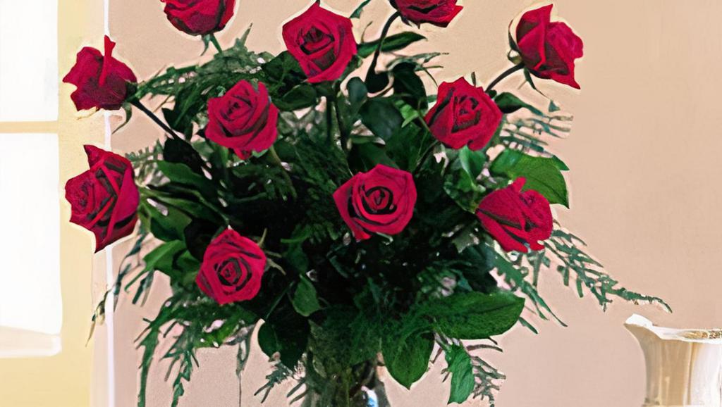 Joy Of Roses Bouquet · A joyful gesture of love and affection, this chic arrangement of one dozen  Red roses with fresh greens is a special surprise on any occasion. Red rose are arranged with leatherleaf fern, huckleberry and variegated pittosporum. Delivered in a clear vase. Standard: 24 1/2