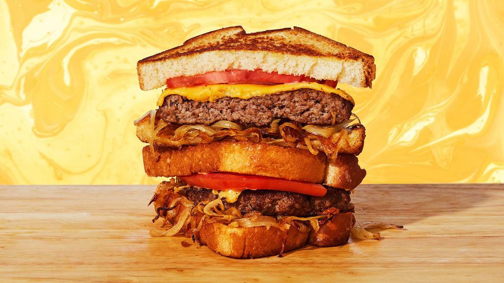 Burger Grilled Cheese · Melted cheddar cheese, beef burger patty, caramelized onions, tomato, and mayo between two slices of buttery grilled bread.