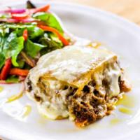 Pastelon De Carne · Mashed ripe plantains layered with beef and cheese. Served with salad.